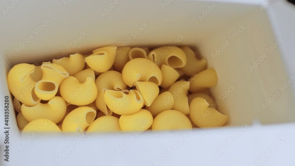 Italian durum wheat pasta poured from white box on the table Italian durum wheat pasta poured from white box on the table