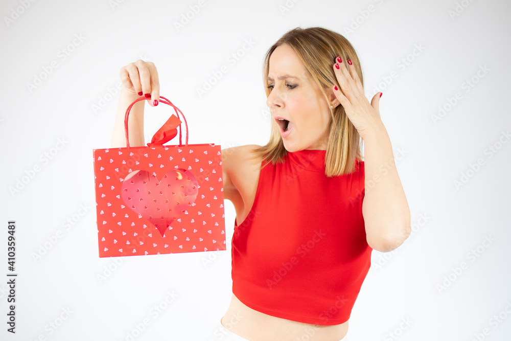 Young surprised woman holding a red bag over white background. Young surprised woman holding a red bag over white background.