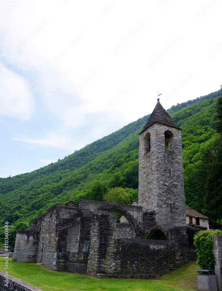 Medieval stone church in Ticino, Switzerland, with a vegetated mountain in background