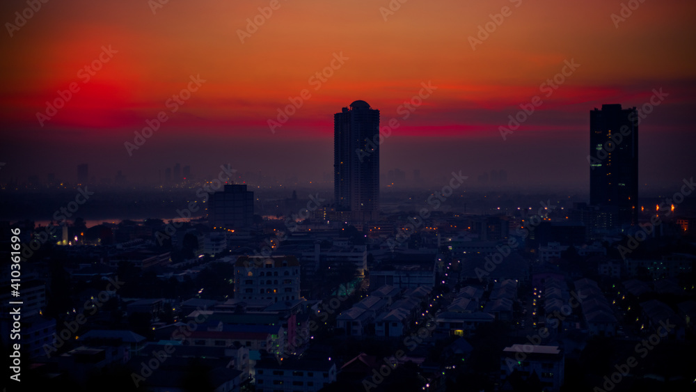 Fototapeta premium The high angle background of the city view with the secret light of the evening, blurring of night lights, showing the distribution of condominiums, dense homes in the capital community