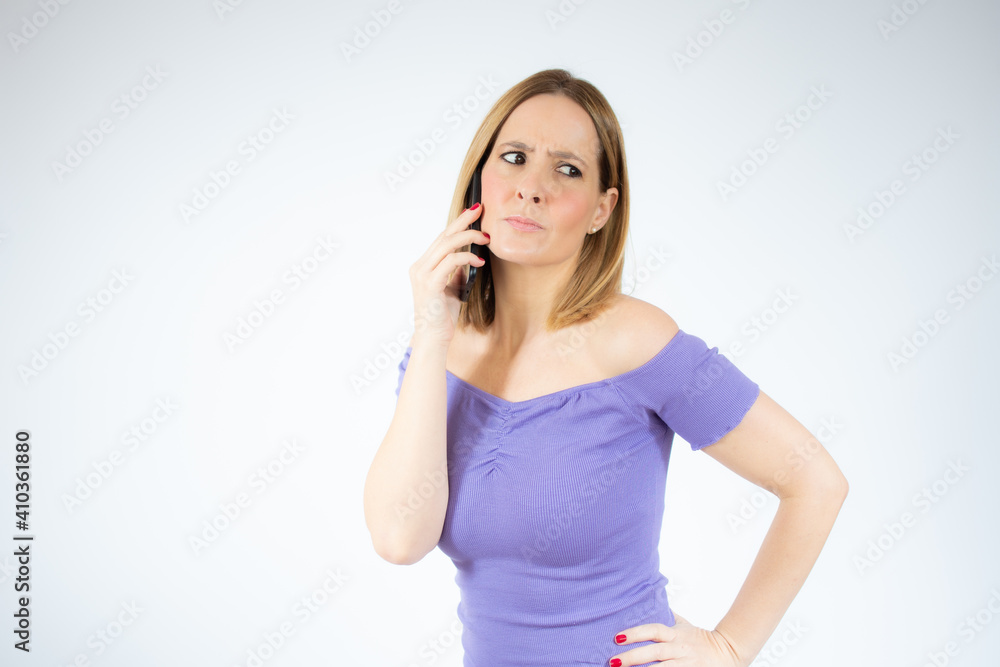 Smiling young woman talking with mobile phone against isolated white background Smiling young woman talking with mobile phone against isolated white background
