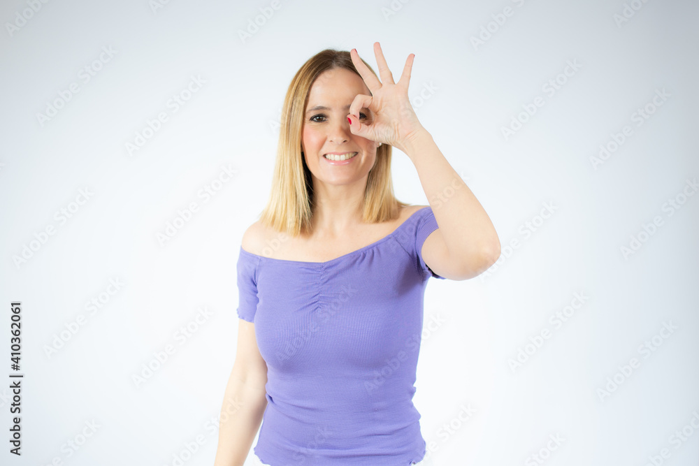 Beautiful woman standing over isolated background doing okay sign with fingers, excellent symbol.