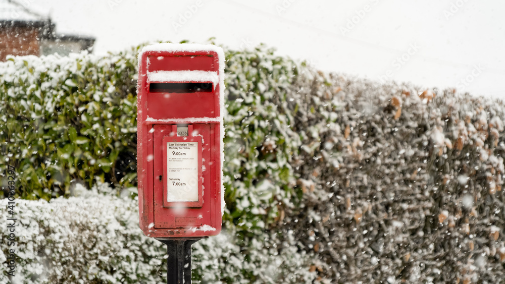 Red post box at Christmas covered with falling snow Red post box at Christmas covered with falling snow