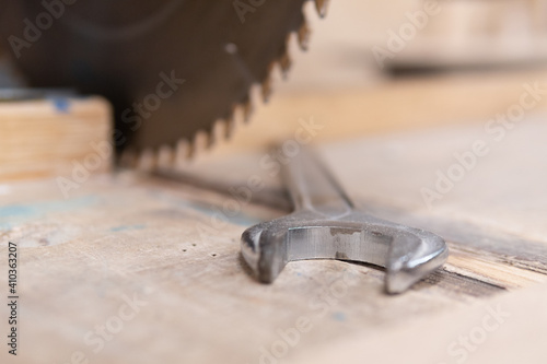Wrench in front of saw. Blurry woodworking saw. Not safe work. Unsafe work,