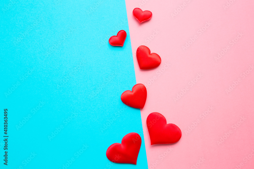Bright red textile hearts in middle on light blue pink table background. Pastel color. Love concept of boys and girls or men and women. Couples relationships. Closeup. Top down view.