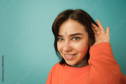 Smilng  close up. Caucasian woman s portrait isolated on blue background with copyspace. Beautiful female model in orange hoodie. Concept of human emotions  facial expression  sales  ad  fashion.