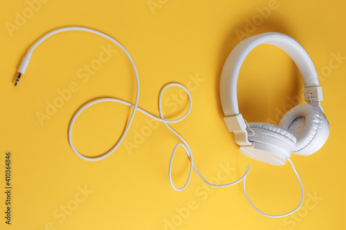 Photo of white headphone on yellow background. Music concept.