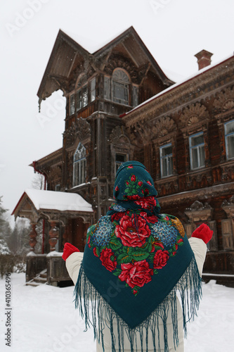 Russian woman, girl. Pogorelovo terem. Wooden house with carved windows, ornamental frames in Pogorelovo village, Chukhloma, Kostroma region, Russia. Russian style in fashion, architecture. Landmark photo