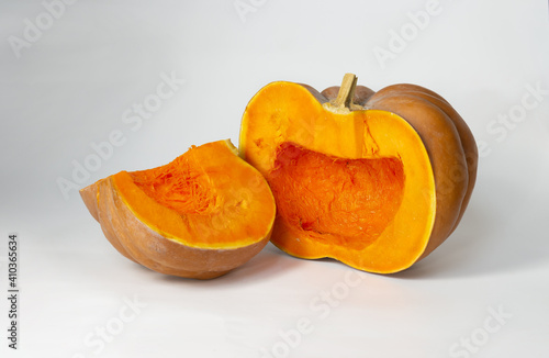 Bright orange pumpkin cut into pieces on a light background