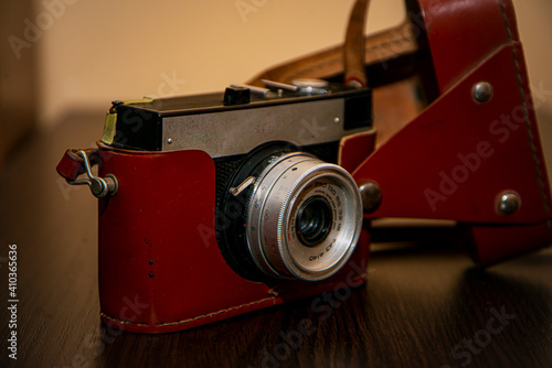 old camera on a wooden table, photographic equipment, retro camera on a brown background, vintage camera, leather case, brown antique