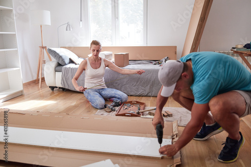 Husband and wife assembling new furniture - renovation home concept.