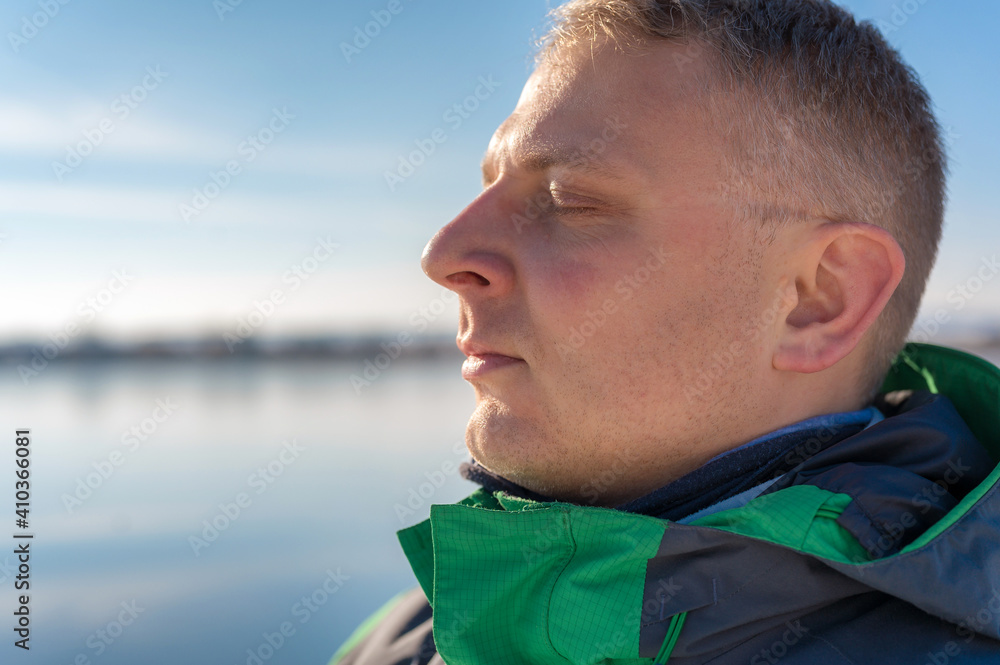 Junger Mann atmet an der frischen Luft tief durch und genießt die Sonne Junger Mann atmet an der frischen Luft tief durch und genießt die Sonne
