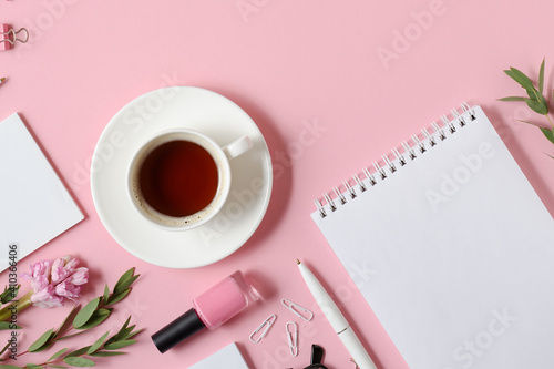Workplace with notepad, pen, coffee cup and other accessories on pink background