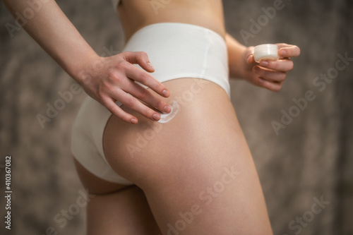 Photo Body care. Woman applying cream on legs and buttocks.