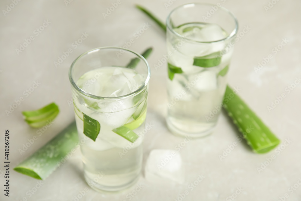 Fresh aloe drink in glasses and leaves on light table Fresh aloe drink in glasses and leaves on light table
