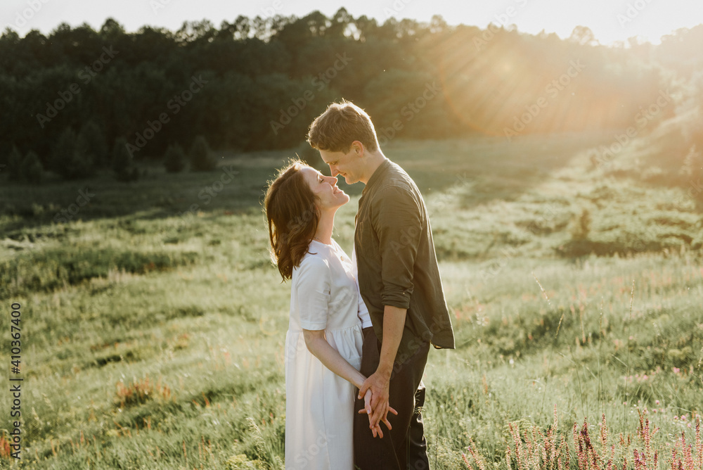 Young beautiful woman and man hug, kiss and walk in nature at sunset. Young beautiful woman and man hug, kiss and walk in nature at sunset.