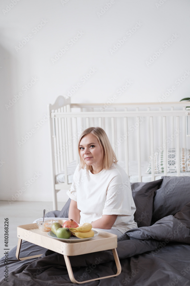 Young beautiful woman having breakfast in bed with coffee and croissant and fresh fruits in cozy bedroom. Morning rituals. Young beautiful woman having breakfast in bed with coffee and croissant and fresh fruits in cozy bedroom. Morning rituals.