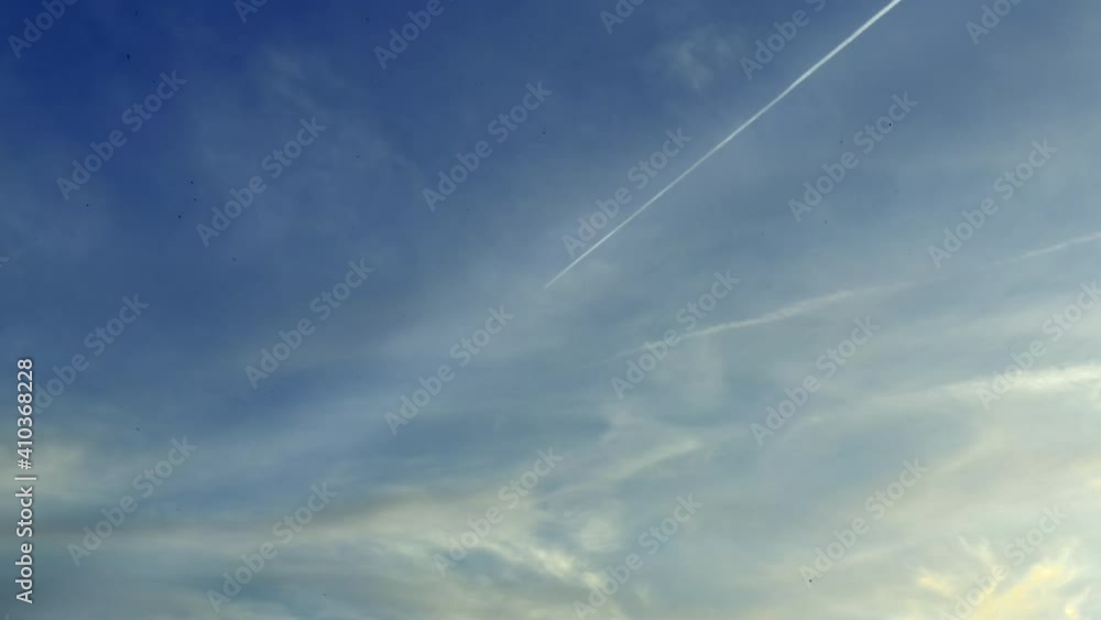 A Flying Airplane Leaves Contrails In A Beautiful Blue Sky With Clouds During The Day A Flying Airplane Leaves Contrails In A Beautiful Blue Sky With Clouds During The Day