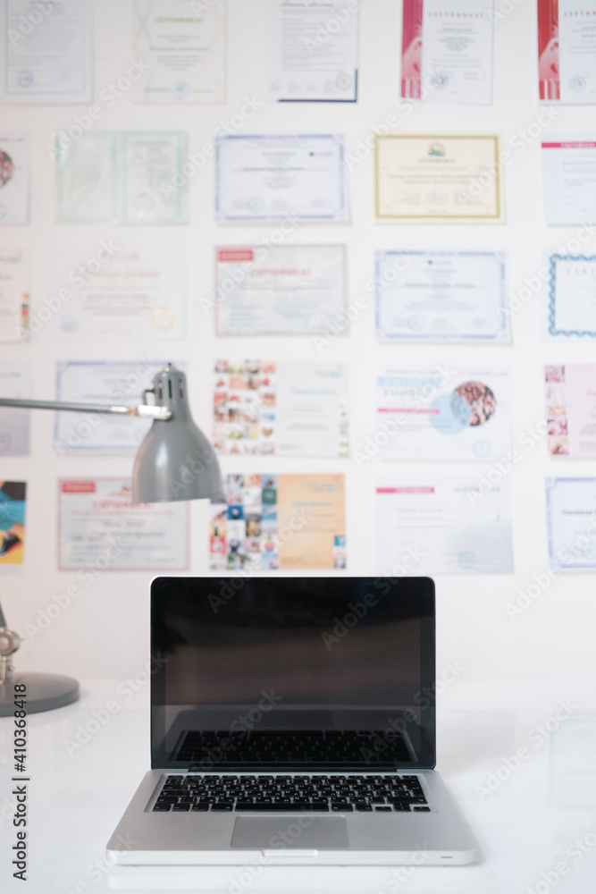 Laptop on the table in the doctor's office. There are certificates on the wall. Laptop on the table in the doctor's office. There are certificates on the wall.
