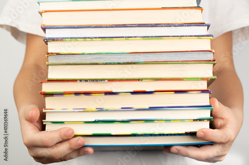 On a light background, a blurred image of a child holding a large stack of books.