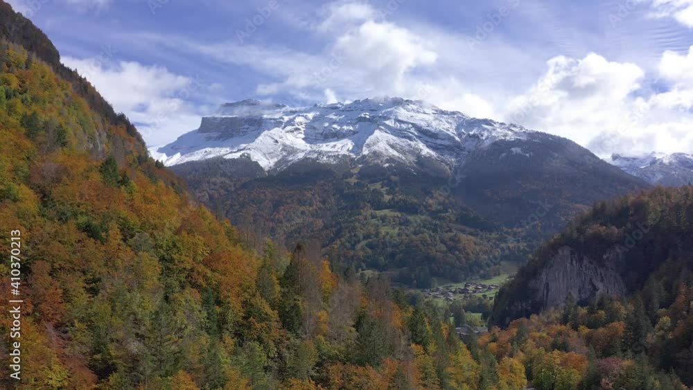 Mountain Covered In Autumnal Forest With Snow-capped Mountain In Background In Sixt-Fer-a-Cheval, France. - aerial pullback Mountain Covered In Autumnal Forest With Snow-capped Mountain In Background In Sixt-Fer-a-Cheval, France. - aerial pullback