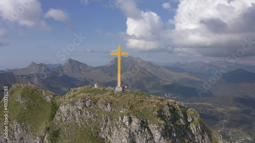 Hikers Stand Next To Yellow Cross On Top Of Pointe de Marcelly Mountain In France. - aerial orbit photo