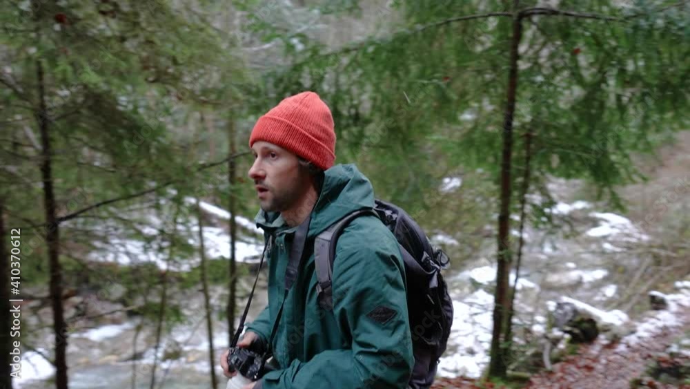 Photographer With Backpack And Camera Walking Deep In Forest During Snowfall In Winter. - reveal, tracking shot Photographer With Backpack And Camera Walking Deep In Forest During Snowfall In Winter. - reveal, tracking shot