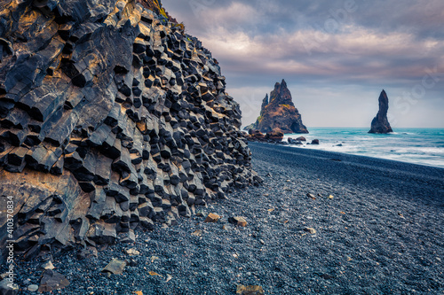 Dramatic Atlantic scenery. Gloomy evening view of Reynisdrangar cliffs in Atlantic ocean. Spectacular sunset on black sand beach in Iceland, Vik location.  Beauty of nature concept background. photo