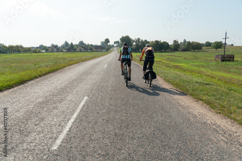 Grodno, Belarus, 16 July 2020: Two cyclists ride on an asphalt road. Cycling around the countryside. Cycling as a way of spending time and a healthy lifestyle.
