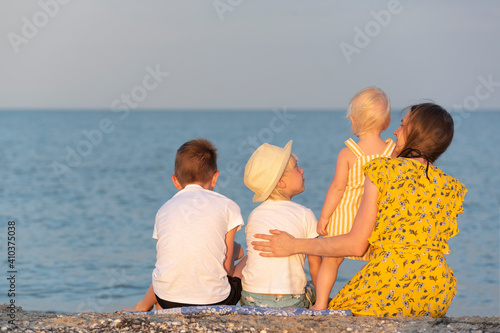 Mom and three children are resting on the seashore. Large family at sea. Summer holidays