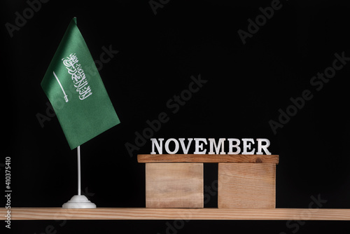Wooden calendar of November with Saudi Arabia flag on black background. Dates of Saudi Arabia in November
