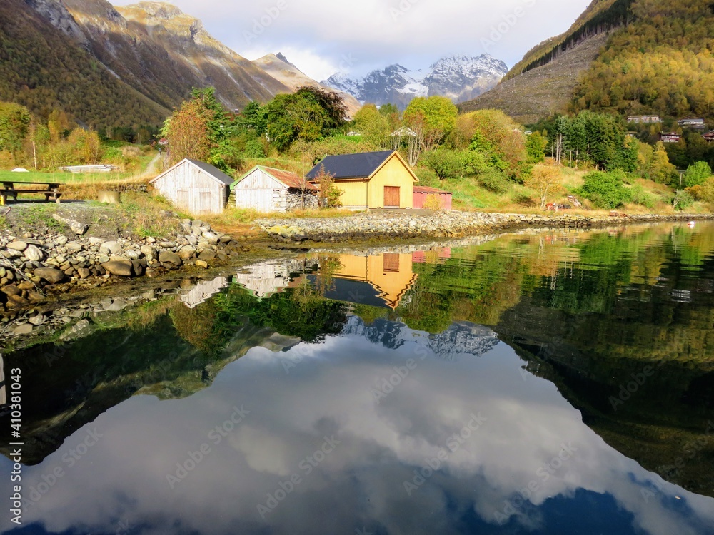 Mirror reflection of village wooden sheds on the water in Urke, Norway