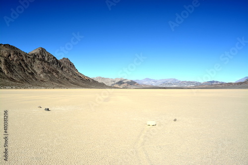 moving stones on the Racetrack Playa leaving tracks in the dry and cracked terrain in the Death Valley National Park, recflections of the sun