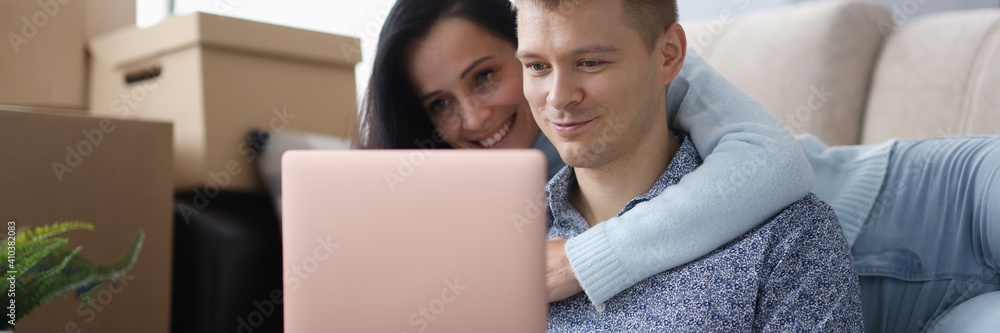 Man and a woman are looking at laptop next to boxes. Finding accommodation for travelers Man and a woman are looking at laptop next to boxes. Finding accommodation for travelers