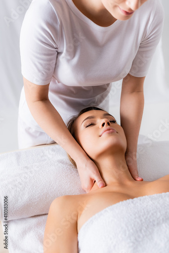 female masseur doing neck massage to pleased client in spa salon