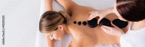 Obraz Top view of young woman getting hot stone massage in spa salon, banner