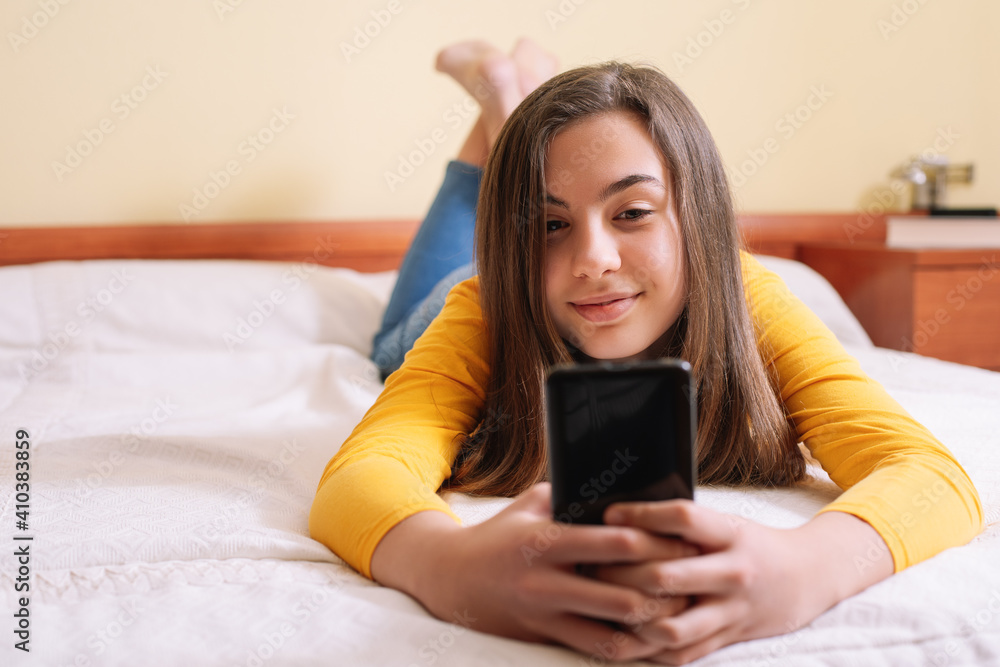 Young woman with mobile phone lying in bed Young woman with mobile phone lying in bed