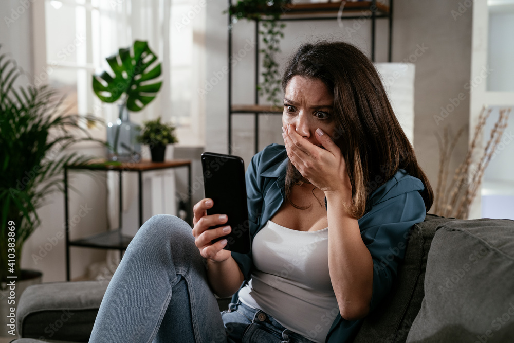 Sad woman sitting on the couch, using the phone. Upset woman waiting for a phone call. Sad woman sitting on the couch, using the phone. Upset woman waiting for a phone call.