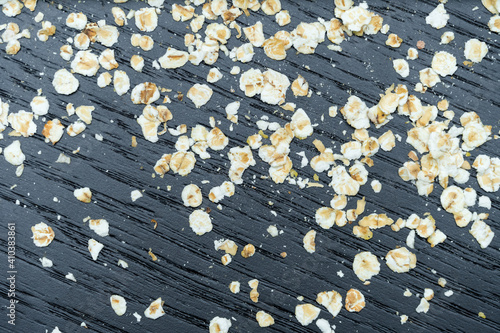 Dry oat flakes on a dark background close-up, top view. Background of dry oatmeal