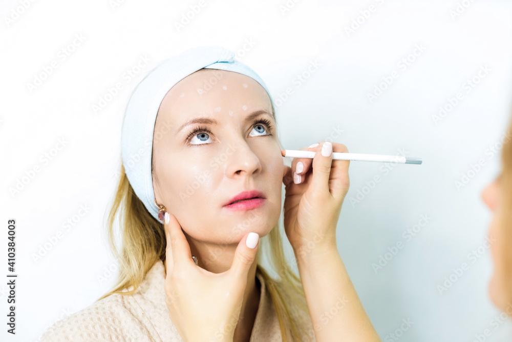 Woman at a beautician's appointment. A specialist examines it and makes markings with a special pencil. Non-surgical face lifting. SMAS lifting ultrasonic. Facelift Woman at a beautician's appointment. A specialist examines it and makes markings with a special pencil. Non-surgical face lifting. SMAS lifting ultrasonic. Facelift