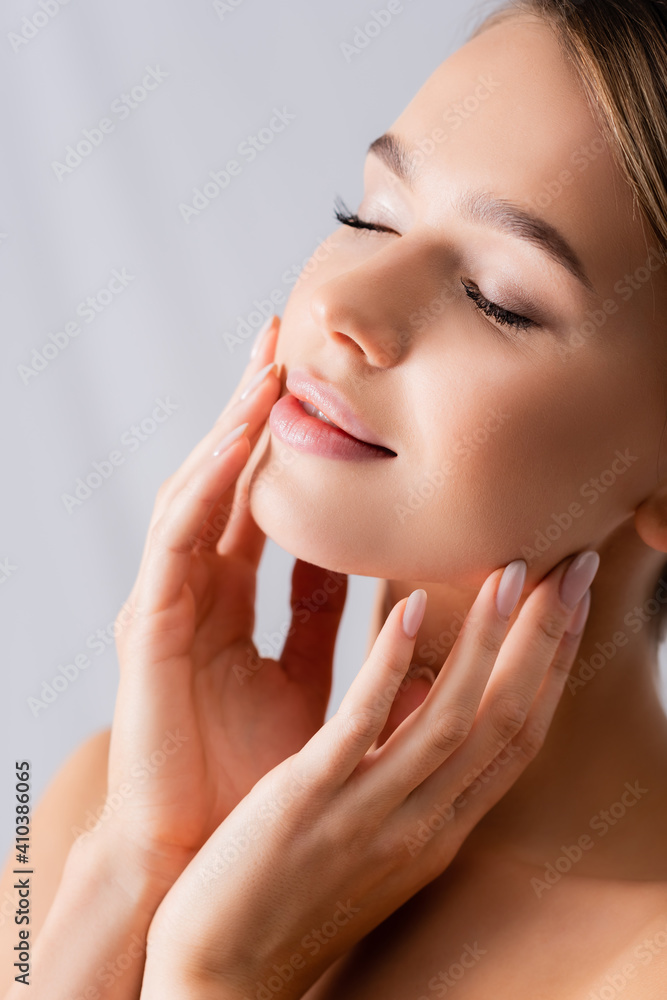 young woman with closed eyes touching face on white young woman with closed eyes touching face on white