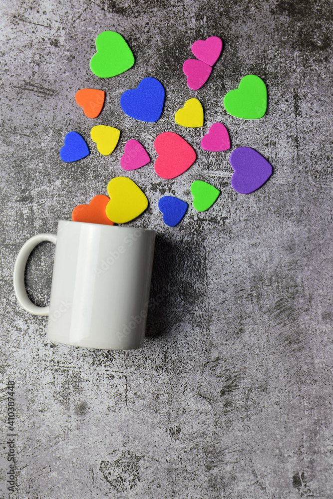 Valentine, love, special day. Multi-colored hearts, with a white cup next to it. Stone background and copy space. Valentine, love, special day. Multi-colored hearts, with a white cup next to it. Stone background and copy space.