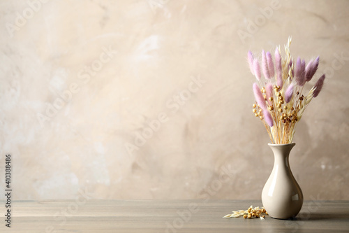 Fotografia Dried flowers in vase on table against light grey background