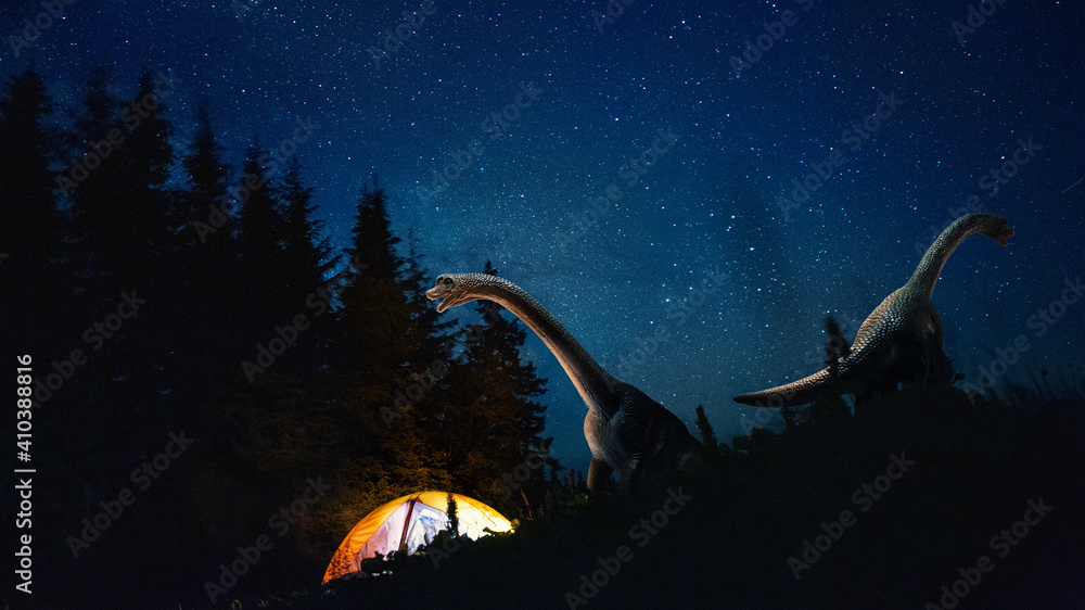 Dinosaurs huge higth walking through the night forest comes across tourists group in travel tent. Evolution and paleontology, dreamworld. Looks interested, careful. Meeting of eras. Jurassic period.