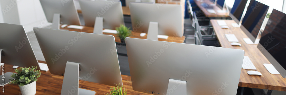 Many silver monitors stand on a wooden table in office closeup. Programmer professional education concept Many silver monitors stand on a wooden table in office closeup. Programmer professional education concept