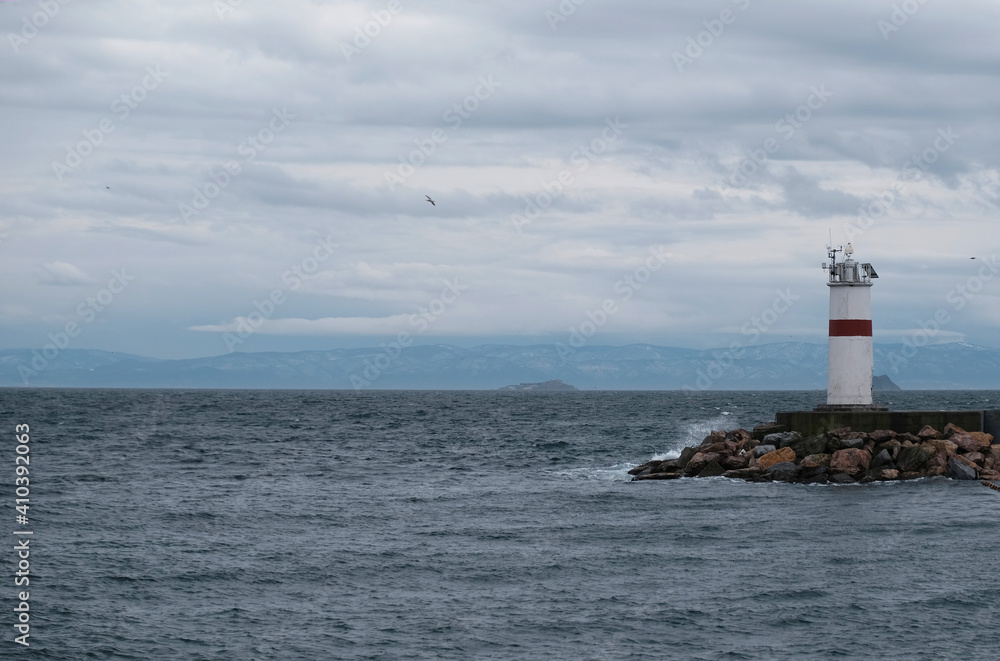 Panorama of the lighthouse on a cloudy day in Istanbul, Turkey. One of the lighthouses on the breakwaters. Advertising banner or poster with copy space. Flying seagulls. Bosphorus and Sea of Marmara.
