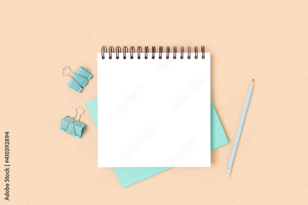 Minimal workspace with square notepad mockup and stationery on a beige background. School concept. Minimal workspace with square notepad mockup and stationery on a beige background. School concept.