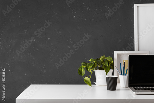 Desk at home office with supplies, laptop and black wall copy space. Stylish workspace.	 photo