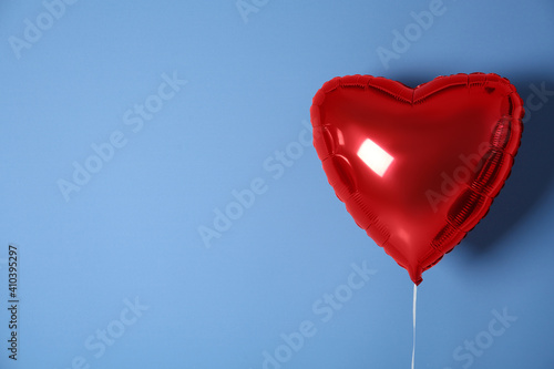 Red heart shaped balloon on blue background, space for text. Valentine's Day celebration