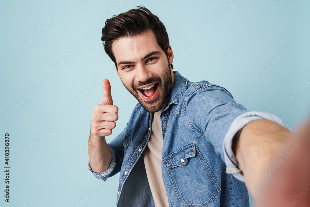 Young excited man showing thumb up while taking selfie photo Young excited man showing thumb up while taking selfie photo